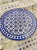 Close-up of a blue and white circular mosaic tile design, featuring the artistic details of a handcrafted Moroccan table.