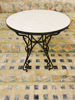 Elegant round coffee table with a marble top, set on a tiled floor, featuring handcrafted Moroccan Zellige mosaic patterns.