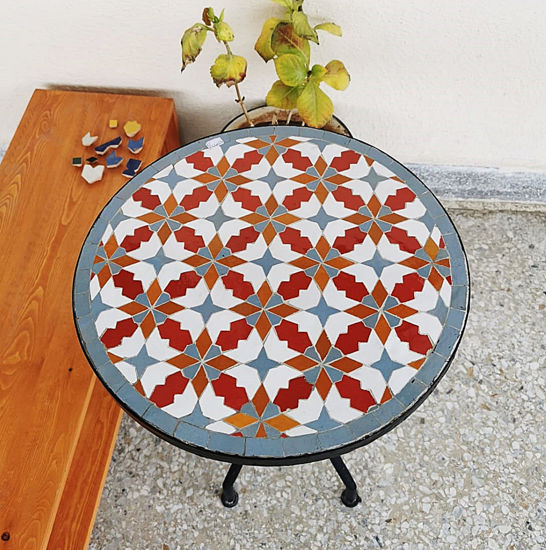 Colorful handmade Moroccan tile table with a plant on top, showcasing vibrant zellige artwork for indoor or outdoor use.