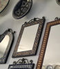 A wall adorned with decorative mirrors and plates, featuring a striking yellow and black Moroccan mosaic wall mirror.