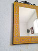 A vibrant yellow mosaic wall mirror, featuring traditional Moroccan zellige tile craftsmanship.