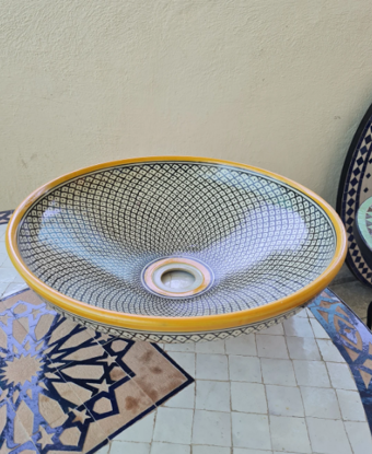 A Moroccan ceramic vessel sink with a yellow rim and black handle, adorned with a fish scale pattern, perfect for stylish bathrooms.