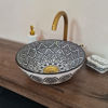 Handmade black and white Moroccan wash basin with intricate patterns and a gold faucet, showcasing Mediterranean elegance.