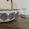 Elegant black and white Moroccan bathroom sink with a gold faucet, highlighting traditional craftsmanship and timeless style.