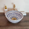 Handmade blue and white ceramic washbasin with a gold faucet, reflecting Moroccan artistry in a modern bathroom setting.