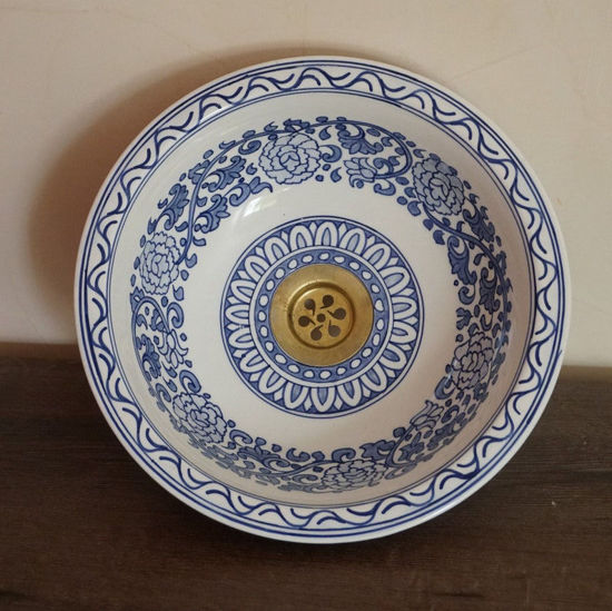 Hand-painted blue and white ceramic sink with a gold handle, showcasing intricate Moroccan designs for elegant bathroom decor.
