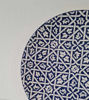 Decorative 14-inch ceramic wall plate from Morocco, handpainted in blue and white with unique geometric designs and textures.
