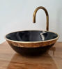 Black ceramic bowl with an aged brass rim and faucet, showcasing Moroccan craftsmanship and intricate sea-scale patterns.