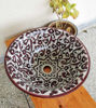 Decorative burgundy ceramic sink featuring detailed Moroccan motifs, blending mid-century modern design with boho elegance.