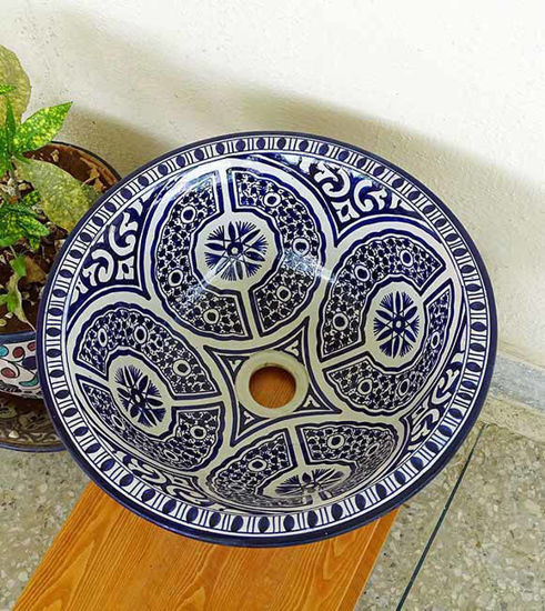 Blue and white ceramic bowl on a wooden table, showcasing intricate Moroccan patterns and a brushed brass rim.