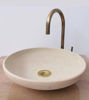 White bowl-shaped vessel sink with a brass faucet, featuring hand-painted Moroccan designs and a soft, neutral patina.