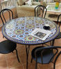 A handcrafted Moroccan mosaic table with colorful tiles, accompanied by chairs.