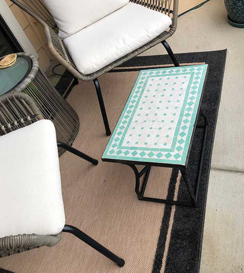 A low rectangular Moroccan mosaic table with colorful tiles, surrounded by chairs, showcasing a unique artistic design.