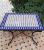 A handcrafted blue and white tile table on a patio, featuring a mid-century design and traditional Moroccan Zellige craftsmanship.