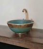 Emerald green ceramic bowl with gold faucet on a wooden counter, showcasing Moroccan fish scale design and artisan craftsmanship.