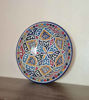 A vibrant, hand-painted Moroccan ceramic plate with intricate patterns, adding cultural flair to any dining experience.