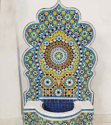 Colorful mosaic fountain featuring blue and yellow tiles, showcasing intricate designs, perfect for outdoor or indoor spaces.