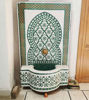 A green and white tiled Moroccan wall fountain, showcasing intricate mosaic patterns, perfect for indoor or outdoor decor.