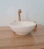 Minimalist white bowl sink topped with a gold faucet, highlighting Moroccan craftsmanship and elegant design for bathrooms.