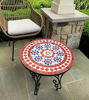 A colorful mosaic table featuring red and blue zellige tiles, set on a patio, showcasing mid-century design.