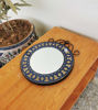 A wooden table displays a vibrant, handmade Moroccan mosaic mirror, showcasing intricate designs and colors.