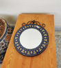 On a wooden table, a decorative Moroccan mosaic mirror reflects vibrant colors and intricate designs, enhancing the space.