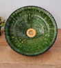 An emerald green Tamegroute ceramic sink with intricate designs rests on a wooden table, adding a touch of rustic elegance