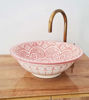 Charming dusty pink ceramic bathroom sink with golden faucet, beautifully hand-painted with Moroccan motifs for a timeless look.