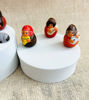 Tiny handmade nativity figurines displayed on a white box, crafted from natural clay with colorful, intricate designs.