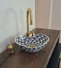 Handmade black and white ceramic sink with detailed Moroccan motifs and a gold faucet, perfect for elegant bathroom styling.