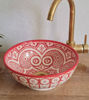Unique pinkish-red Moroccan ceramic sink with traditional designs and a gold faucet, ideal for enhancing bathroom or kitchen decor.
