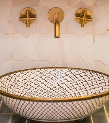 Stylish bathroom sink featuring gold fixtures against a pristine white tile wall, enhancing the room's contemporary design.