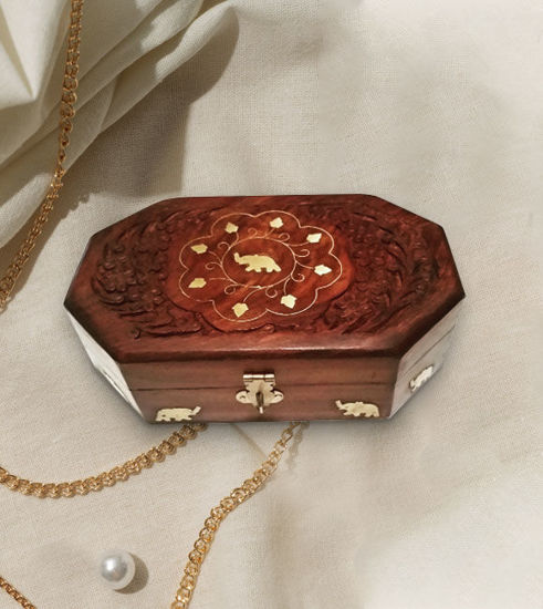 A handcrafted rosewood jewelry box featuring an intricate elephant inlay, adorned with gold chains and pearls for elegance.