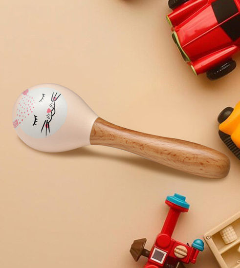A wooden rattle toy featuring a cat face rests beside colorful toy cars, highlighting playful and safe baby toys for infants.