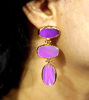 A woman sporting vibrant purple amethyst earrings, crafted from gold-plated brass, highlighting the natural beauty of the stones.