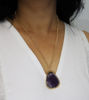 Unique purple amethyst pendant on a gold-tone chain, highlighting the natural beauty and variations of the semi-precious stone.