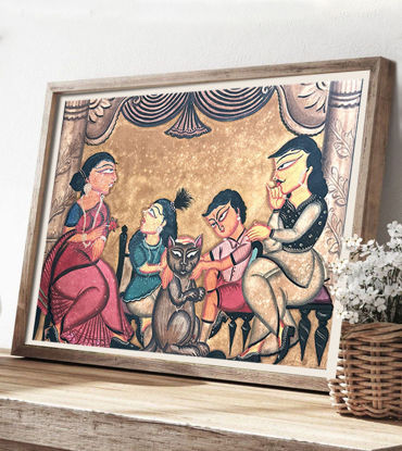 Framed Patachitra painting of a family around a table, featuring vibrant colors and a whimsical cat in a village setting.