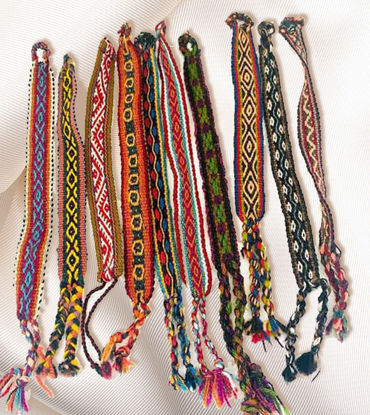 Vibrant handmade bracelets made from Peruvian manta fabric, displayed on white cloth, featuring unique Inca patterns.